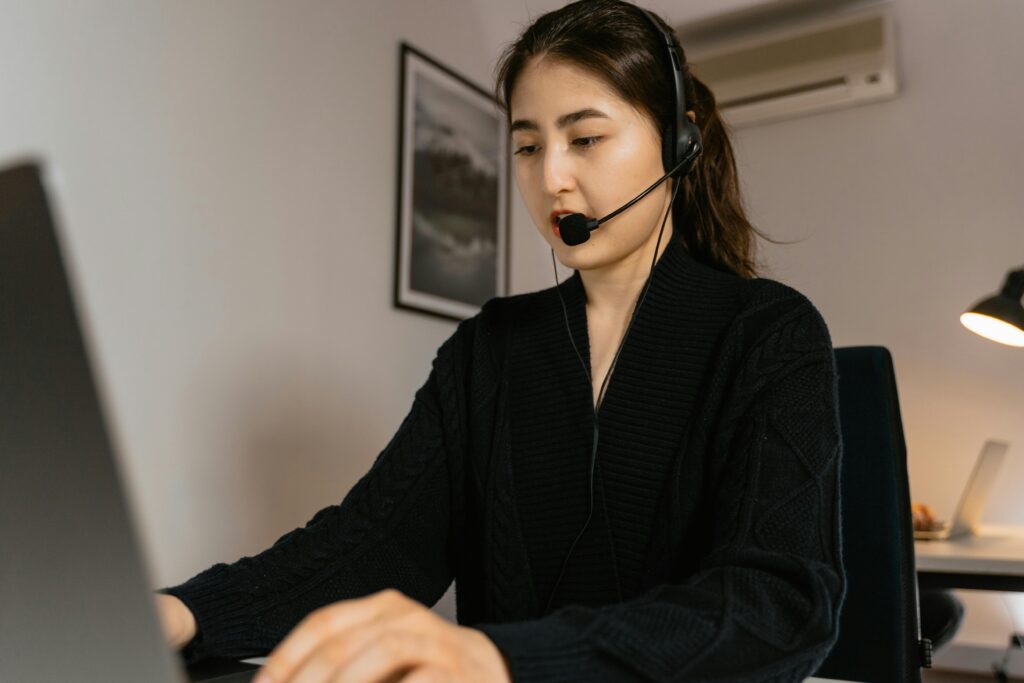 pexels-photo-7709250-7709250 A woman working in a call center, using a laptop and headset for customer service assistance.